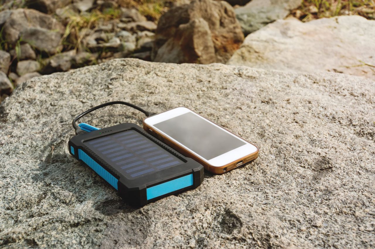 Photo of iPhone and portable solar charger on rocks in sun