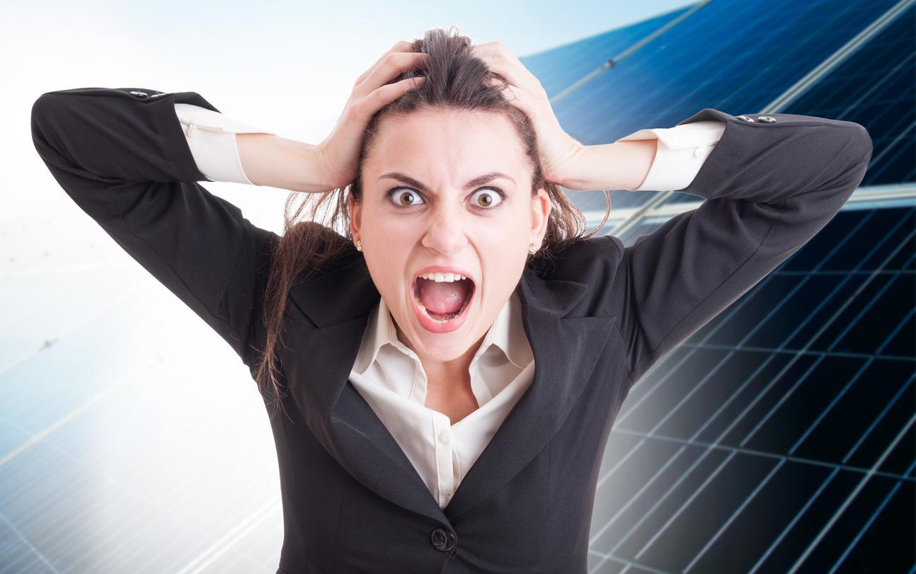 Woman screaming with hands on head in front of solar panels